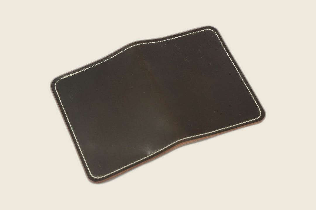 Warden bifold wallet in dark cognac Horween shell cordovan, espresso-brown exterior, cream flat lay