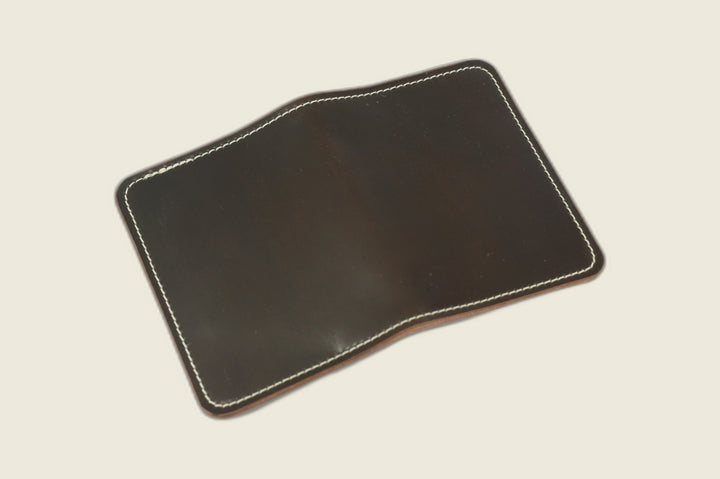 Warden bifold wallet in dark cognac Horween shell cordovan, espresso-brown exterior, cream flat lay