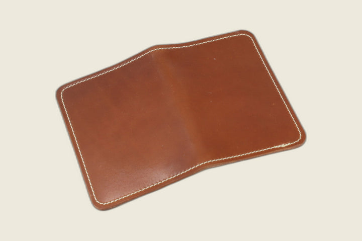 Warden bifold wallet in amaretto Horween shell cordovan laid open flat, exterior view, cream backdrop