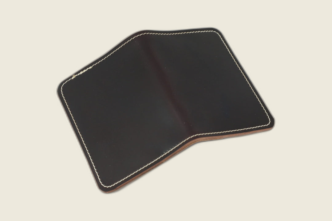 Warden bifold wallet in Color 8 Horween shell cordovan, near-black exterior laid flat, cream backdrop