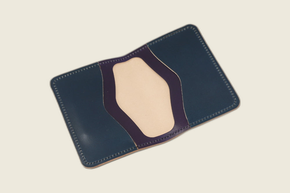 Warden bifold opened to navy shell cordovan card pockets with violet trim over a natural well