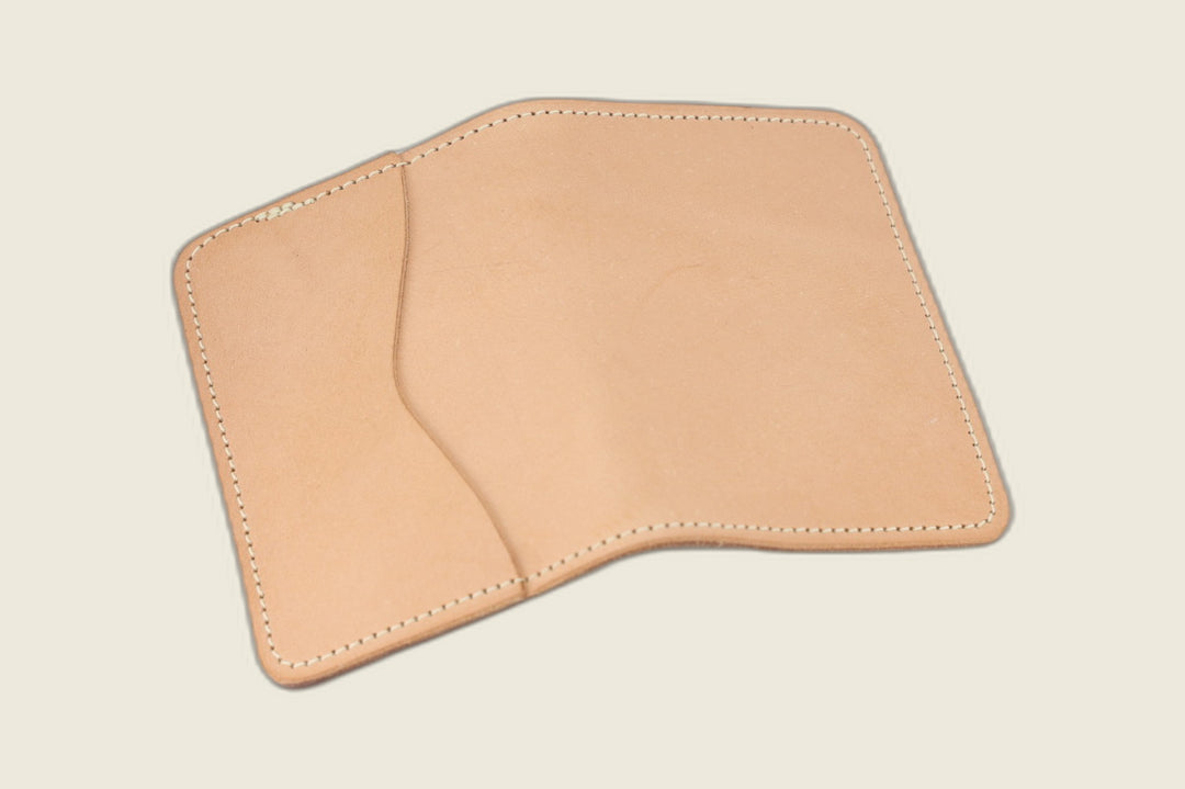 Warden bifold wallet in natural veg tan Hermann Oak steerhide, pale exterior with slip pocket, cream flat lay