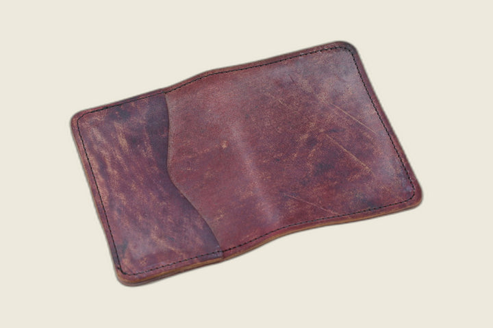 Warden bifold wallet in marbled burgundy Rocado shell cordovan, richly mottled exterior, cream backdrop