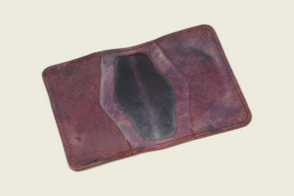 Warden bifold opened to marbled burgundy card pockets around a dark oxblood well