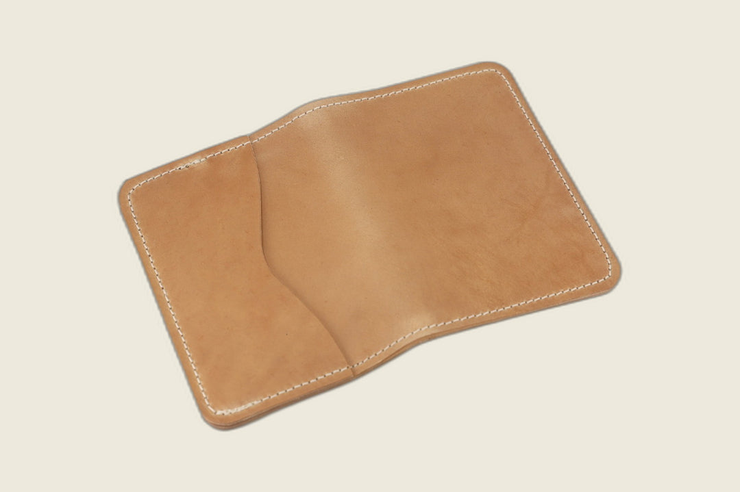 Warden bifold wallet in natural Comipel shell cordovan, golden tan exterior with slip pocket, cream backdrop