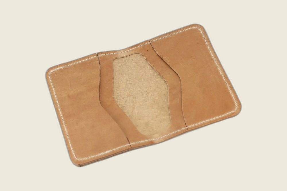 Warden bifold opened to natural Comipel shell card pockets with a pale suede well