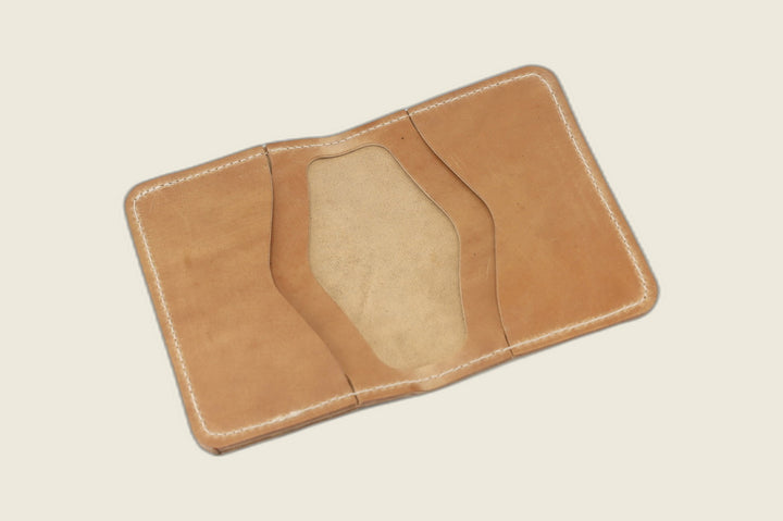 Warden bifold opened to natural Comipel shell card pockets with a pale suede well