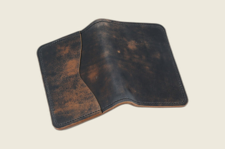 Warden bifold wallet in marbled black Rocado shell cordovan, smoky tan mottling, cream backdrop