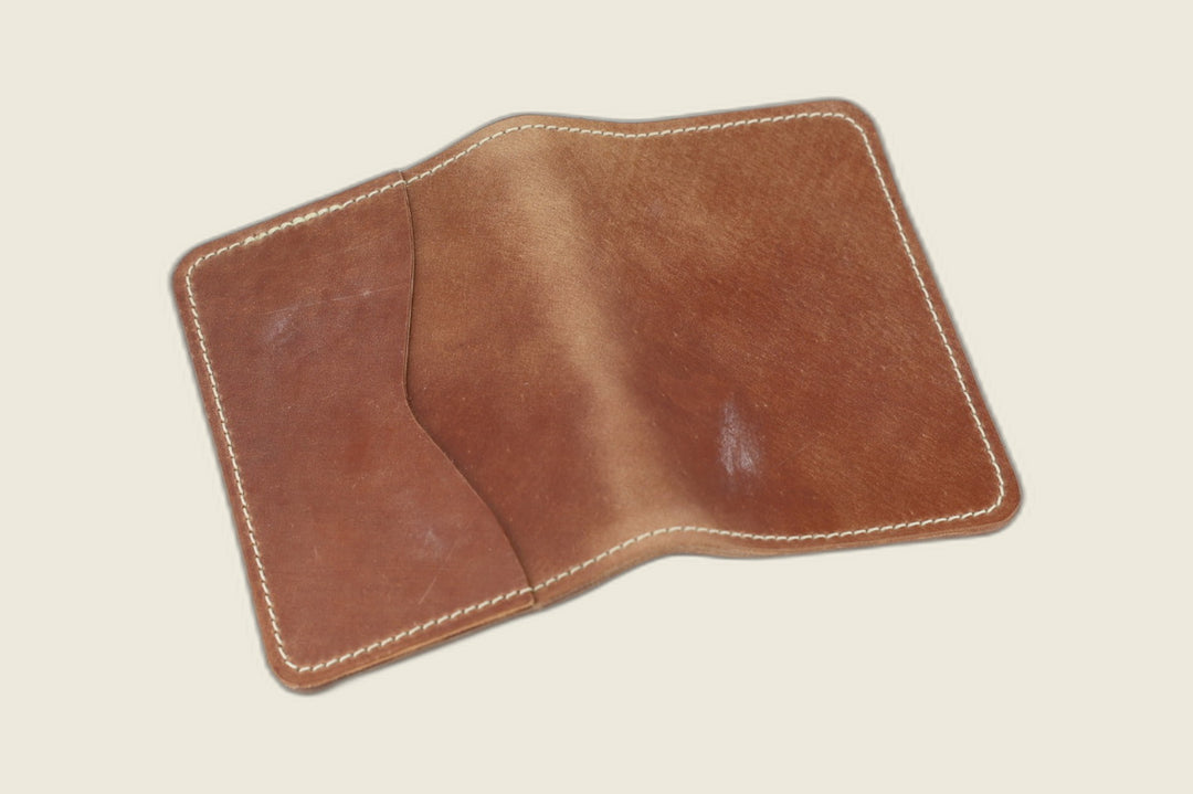 Warden bifold wallet in marbled whiskey Rocado shell cordovan, warm chestnut exterior, cream flat lay