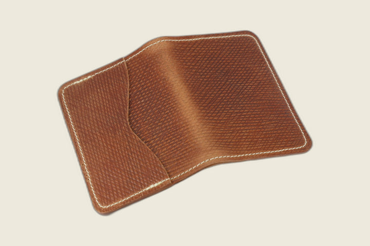 Warden bifold wallet in light brown Russian grain shell cordovan with cream stitching, open showing curved pocket