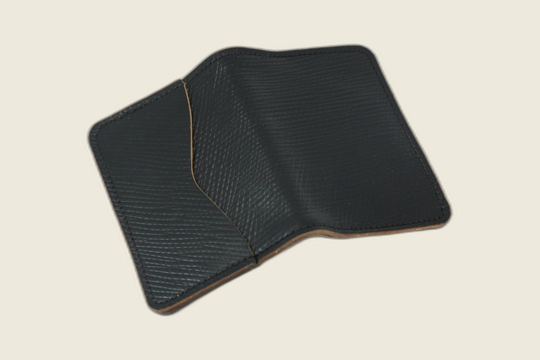 Warden bifold wallet in black Russian grain shell cordovan, open showing hatch-grain panels and curved pocket