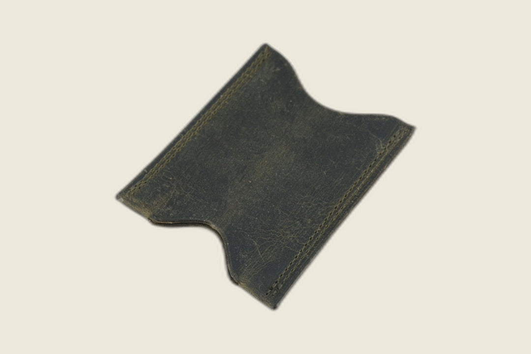 Stonewall card sleeve in matte olive Gallun deerskin with tonal stitching and notched card scoops, angled on cream