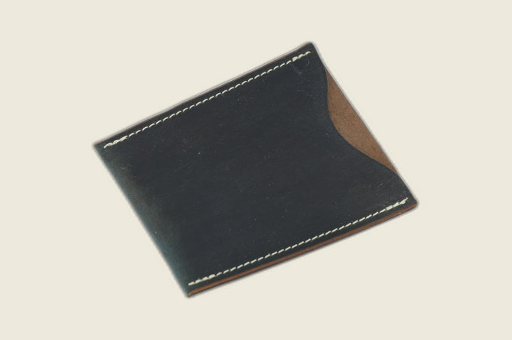 Safeguard sleeve front in Horween navy workshoe butt, near-black sheen with brown suede at the thumb scoop
