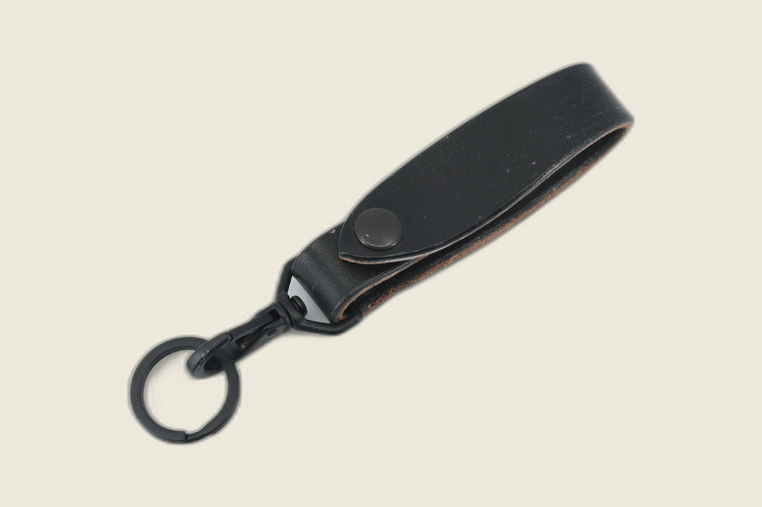 Lanyard in Wickett & Craig black harness leather with matte black snap, swivel hook and key ring, flat lay on cream