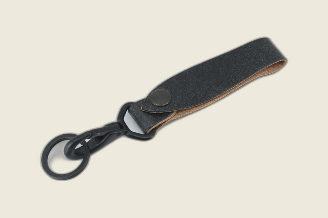 Lanyard in black J&FJ oak harness leather with dark snap, black swivel clasp and key ring, cream backdrop
