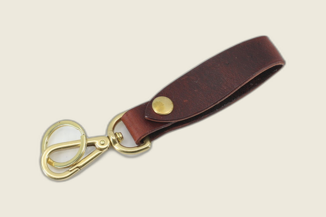 Lanyard in burgundy Gallun four spot deerhide with brass snap, swivel clasp and key ring, cream backdrop