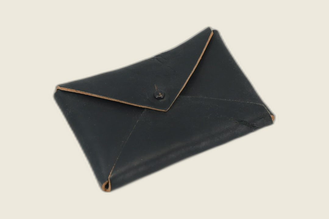 Aegis envelope wallet in black tumbled Horween horsebutt, matte flap with black snap and raw tan edges
