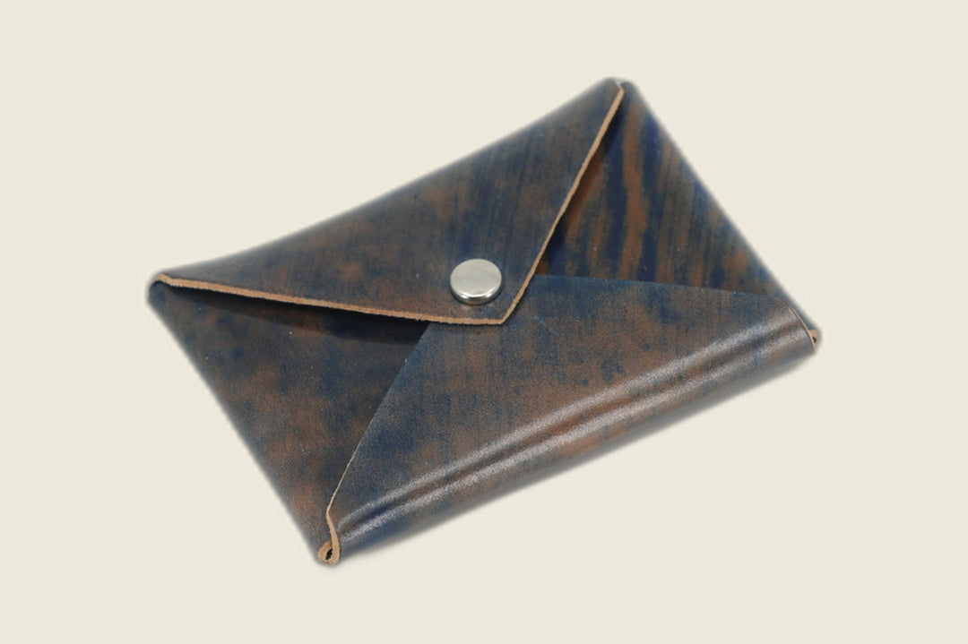 Aegis envelope card wallet in Rocado marbled navy shell cordovan showing blue-brown marbling, closed with nickel snap