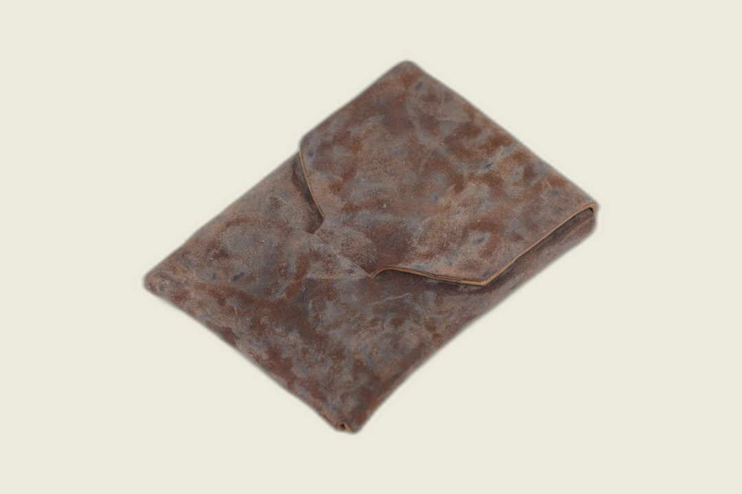 Ward fold-over pouch wallet in distressed tumbled shell cordovan with tuck-in flap, closed on a cream background