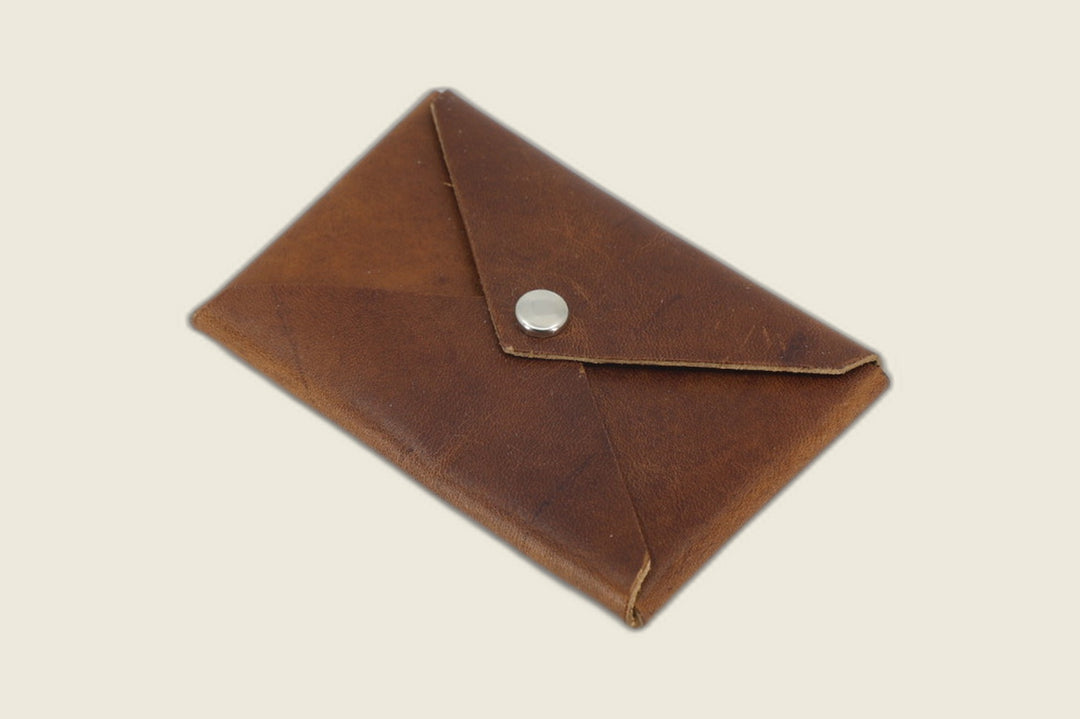 Aegis envelope card wallet in Horween brown nut Cypress horsehide with rich patina and nickel snap, angled flat lay