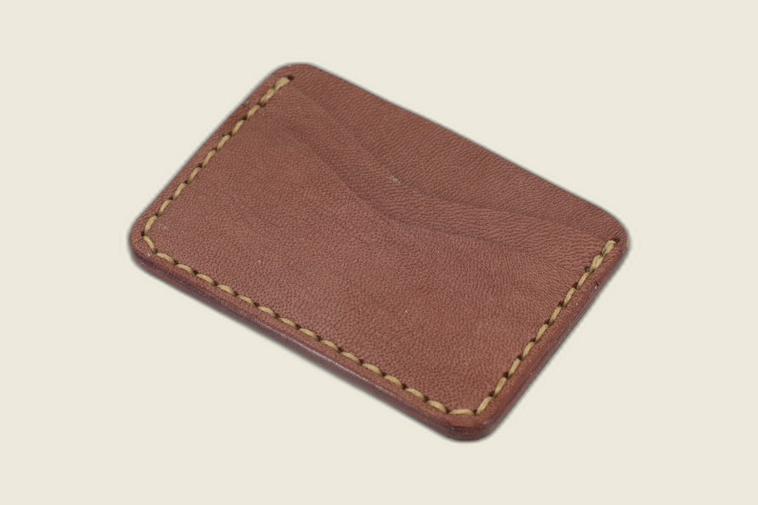 Buckler four-slot card holder in pebbled sand brown goat with tan saddle stitching, curved slots facing up