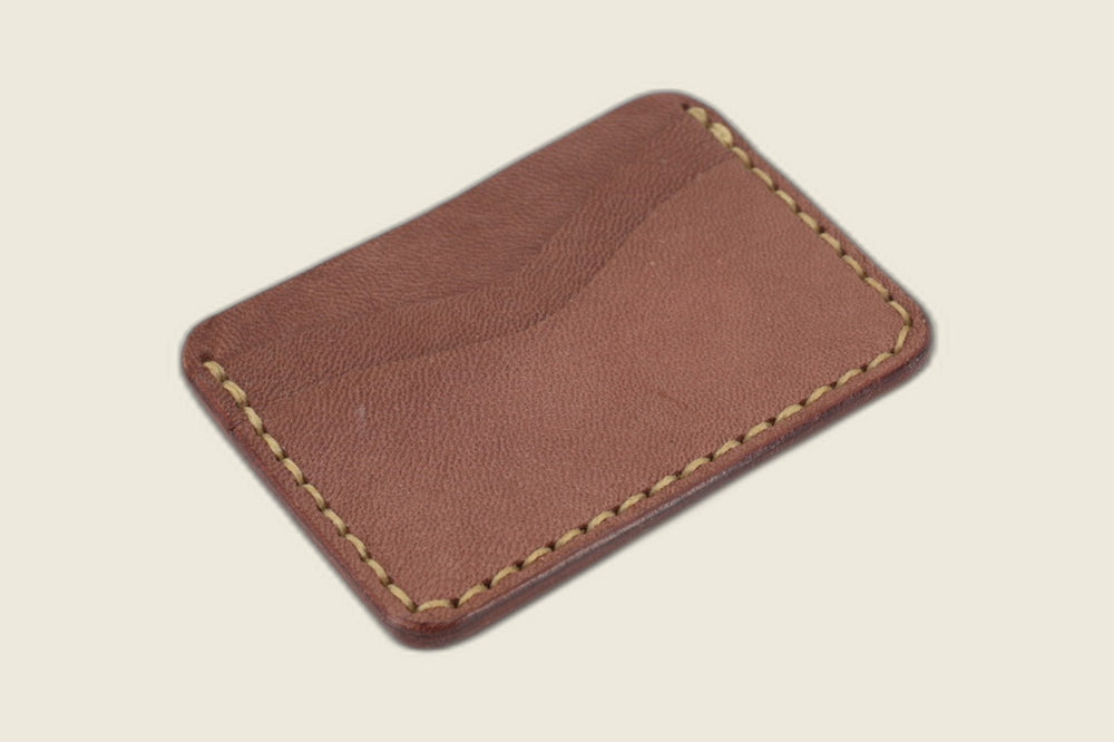 Back of the Buckler sand brown goat card holder showing a single curved slot and hand-stitched edges