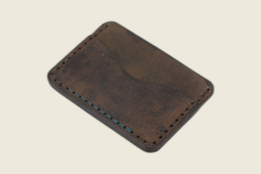 Buckler two-slot card holder in dark patinated brown shell cordovan, curved slot and teal edge stitching visible