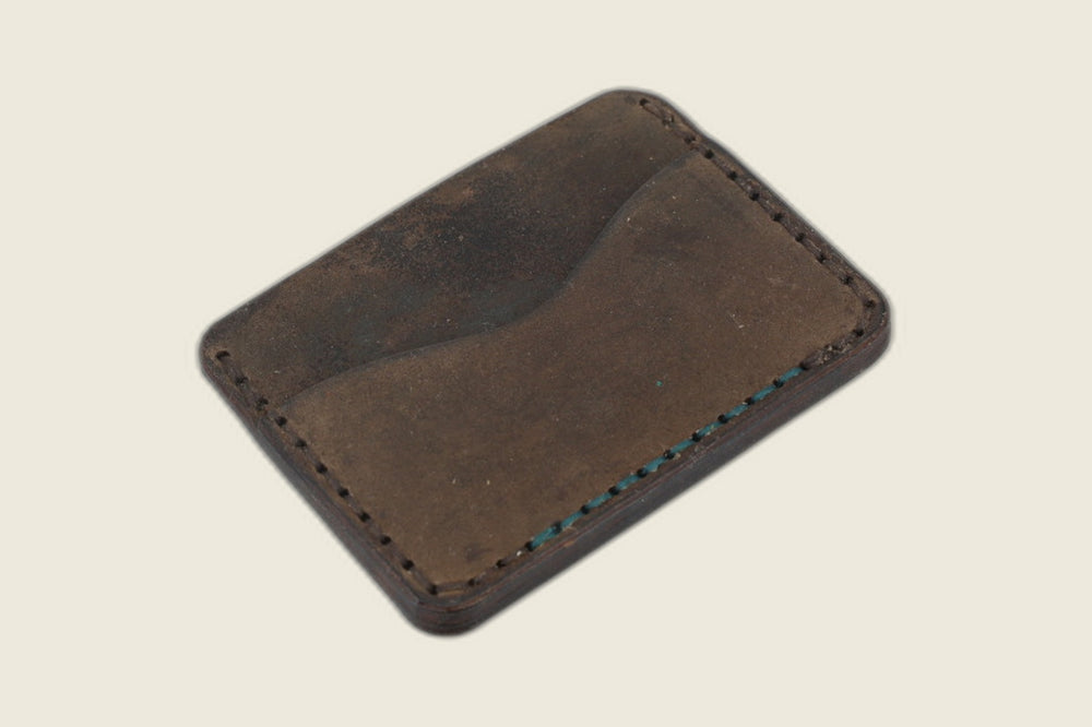 Flip side of the Buckler brown shell cordovan card holder with a curved slot and teal accent stitch row
