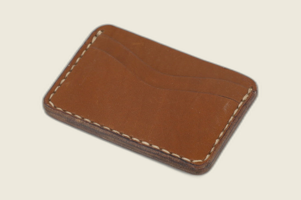 Back of the Buckler Haas caramel calfskin card holder showing one curved slot and hand stitching, on cream