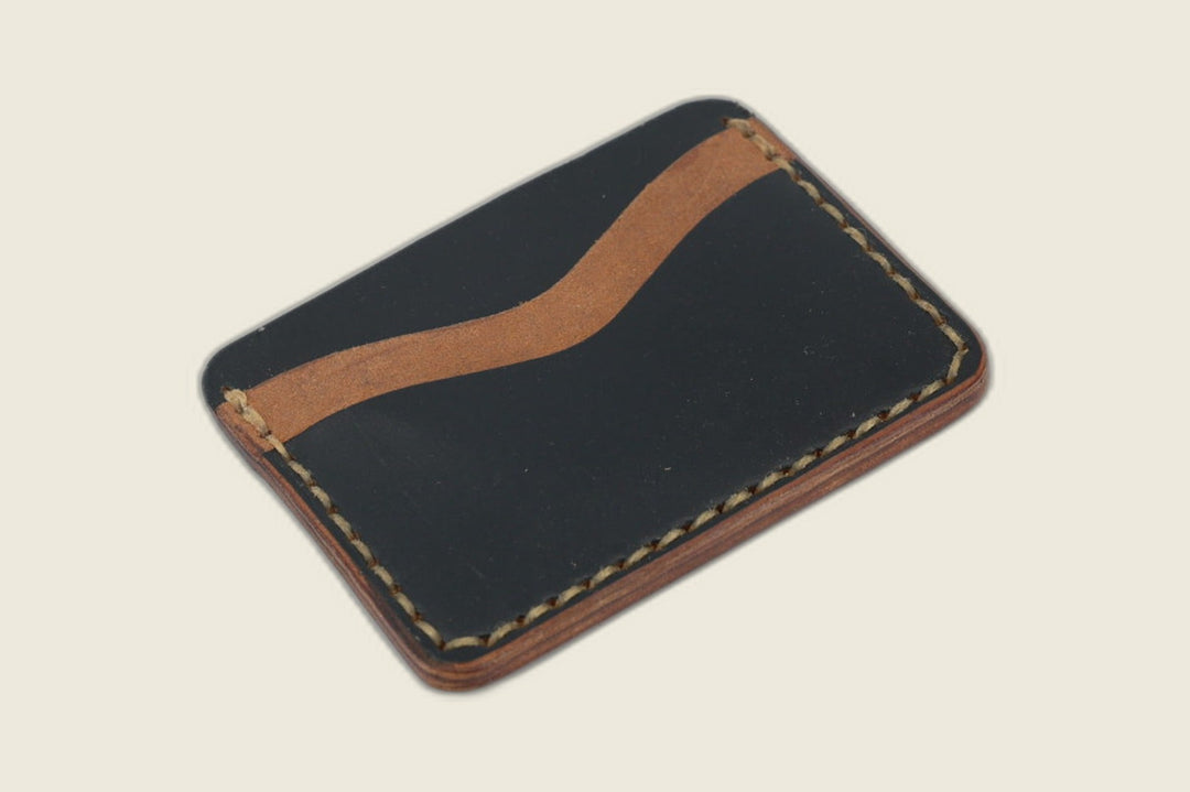 Buckler four-slot card holder in Horween black horsebutt with a contrasting tan slot lining and tan stitching