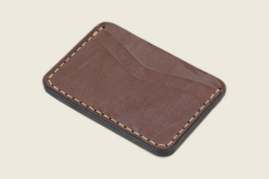 Buckler two-slot card holder in golden steerhide with deep pull-up patina and a curved slot, angled flat lay
