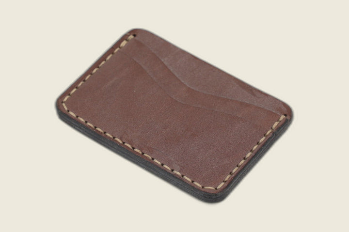 Buckler two-slot card holder in golden steerhide with deep pull-up patina and a curved slot, angled flat lay