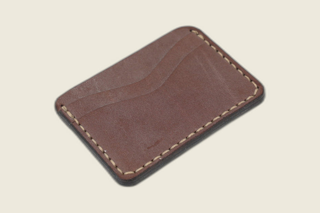 Other side of the Buckler golden steerhide card holder showing its curved slot and teal accent stitching