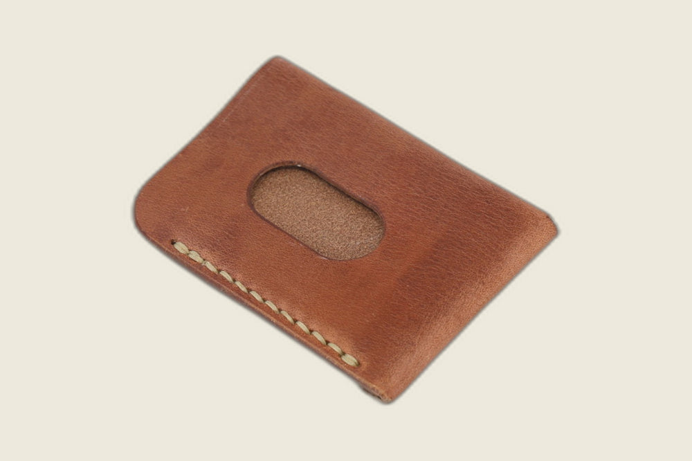 Back of the Vanguard harness leather sleeve with an oval thumb cutout for sliding cards out, on a cream backdrop